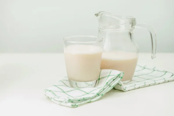 Leche en una jarra de vidrio y vidrio sobre fondo de madera — Foto de Stock