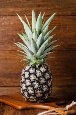 Kahverengi ahşap bir masa üzerinde olgunlaşmış ananas