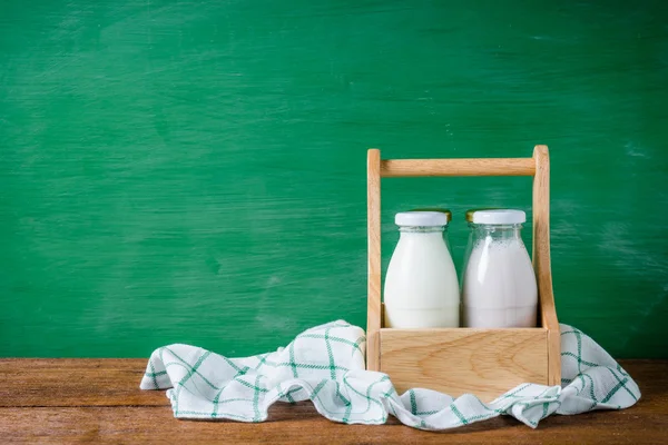 Milk bottles in the box on green background.