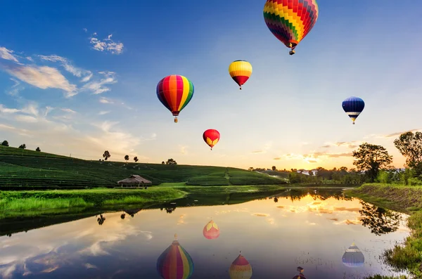 Kleurrijke hete-lucht ballonnen vliegen over thee plantage landschap bij zonsondergang. — Stockfoto