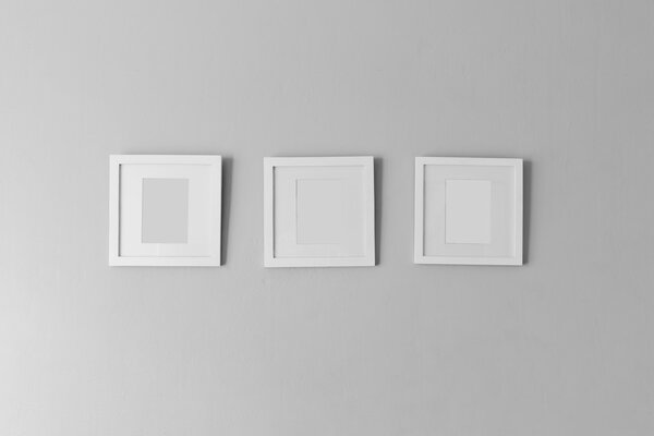 Collage of three white photo frames on the wall