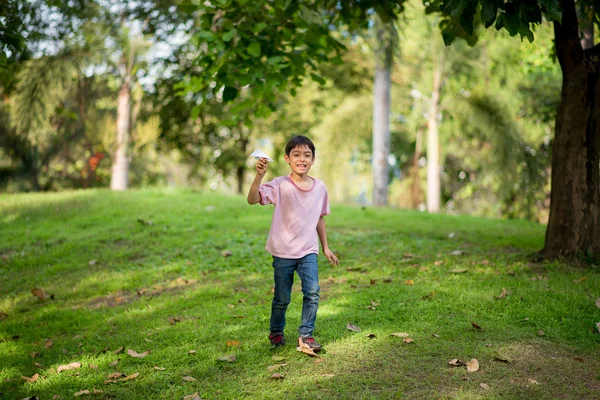 Petit frère jouant du papier avion dans le parc — Photo