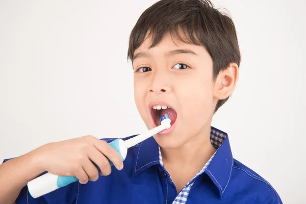 Menino usando escovas de dentes elétricas no fundo branco — Fotografia de Stock