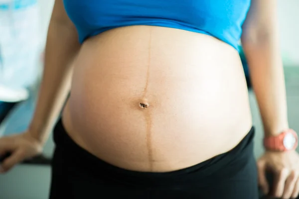 Zbliżenie, brzuch i ręce w ciąży kobiety stojącej — Zdjęcie stockowe