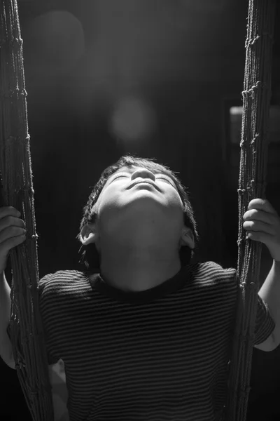 Kisfiú játszik a hinta fedett rim fény fekete-fehér — Stock Fotó