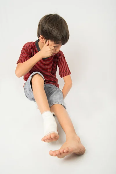 小さな男の子は、応急処置の包帯を必要があります彼の足で事故をしてください。 — ストック写真