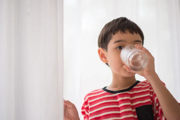 Menino bebendo água casa interior — Fotografia de Stock