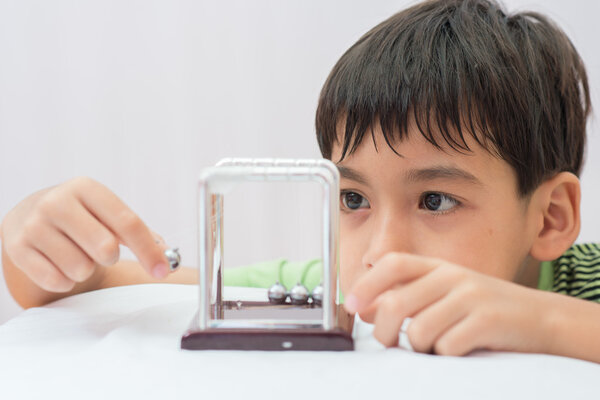 Маленький мальчик изучает Ньютон баланс мяч для физики науки
