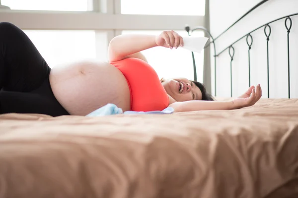 Glad mamma graviditet mage hud nära håll sitta på sängen — Stockfoto