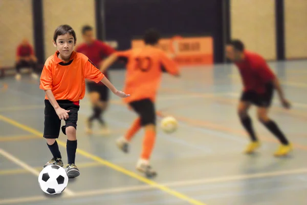 Menino chutando bola de futebol futebol ginásio indoor — Fotografia de Stock