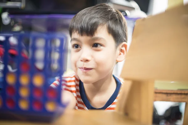 Pequeño niño jugando conectar cuatro juego de enfoque suave en contacto visual — Foto de Stock