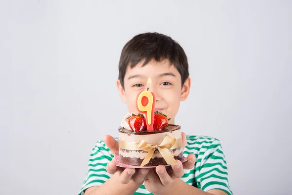 Мальчик задувает свечу на торте на день рождения — стоковое фото