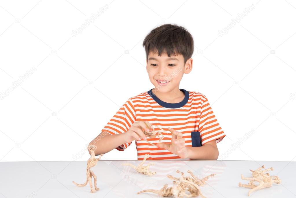 Little boy playing dinosaur fossil toy on the table 