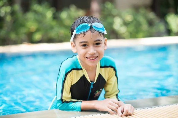 Маленький азиатский арабский мальчик плавает в бассейне отеля на открытом воздухе — стоковое фото