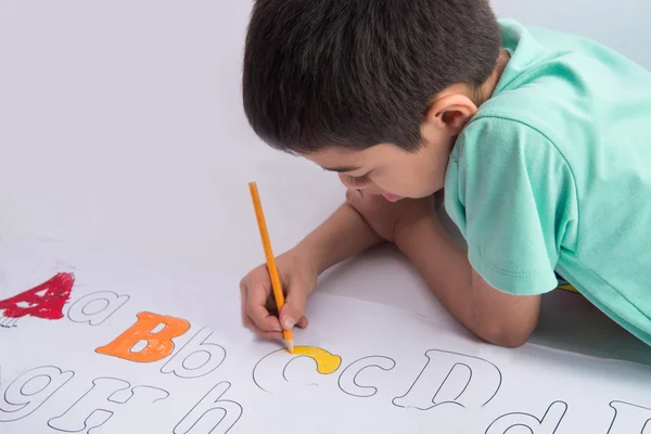 Μικρό παιδί αγόρι ζωγραφική και χρωματισμός αλφάβητο για τις εσωτερικές δραστηριότητές σας χαρτί — Φωτογραφία Αρχείου