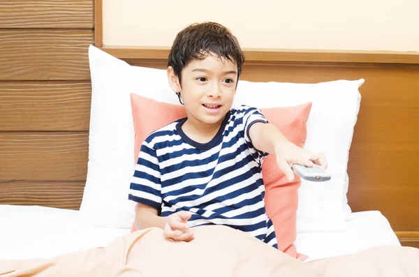 Ragazzino guardando la tv con telecomando in mano — Foto Stock