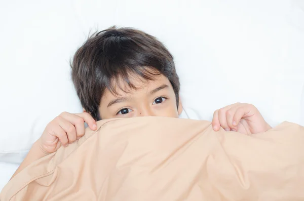 Pequeño niño acostado en la cama con la manta cubierta media cara —  Fotos de Stock