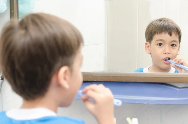 Malý chlapec čistit zuby při pohledu na zrcadlo — Stock fotografie