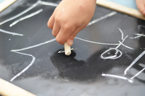 Pequena mão está desenhando em placa de giz — Fotografia de Stock