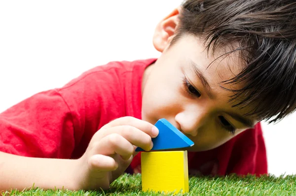 Kleine jongen bouwen van een klein huis met kleurrijke houtblokken — Stockfoto