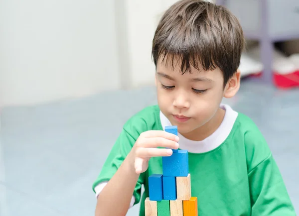 Kleine jongen bouwen van een klein huis met kleurrijke houtblokken — Stockfoto