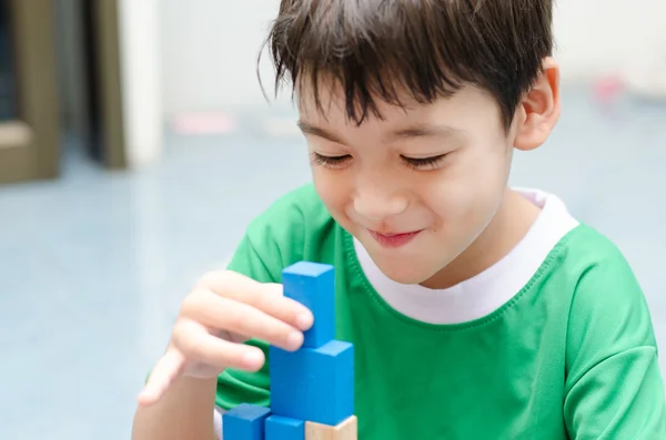 Kleine jongen bouwen van een klein huis met kleurrijke houtblokken — Stockfoto
