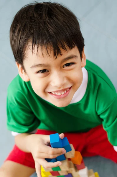 Kleine jongen bouwen van een klein huis met kleurrijke houtblokken — Stockfoto