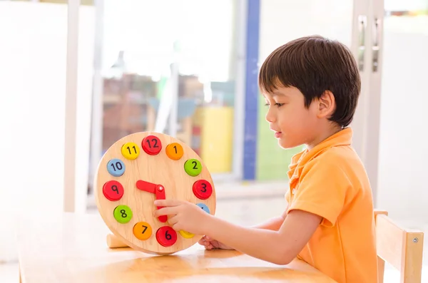 Pequeño niño aprendiendo tiempo con reloj juguete de montessori educationa Fotos De Stock Sin Royalties Gratis