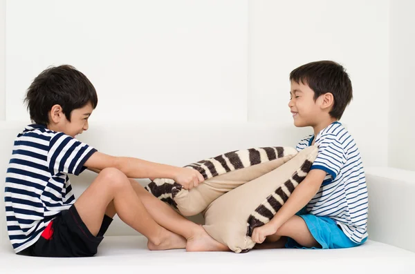 Little sibling boy playing pillow fighting on sofa — Stock Photo, Image