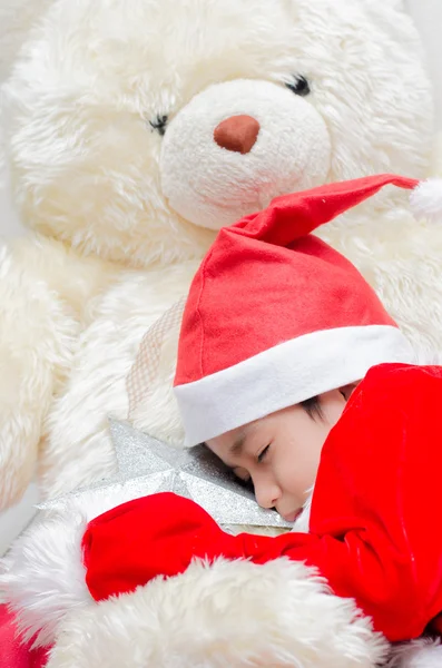 Lille pojken sover på santa klänning med stora björnen — Stockfoto