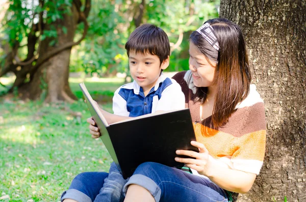 Mutter und Sohn lesen gemeinsam ein Buch im Park — Stockfoto