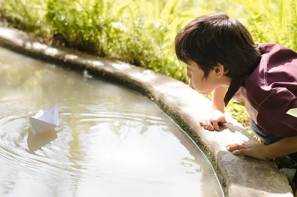 Little boy enjoy blowing paper boat — Stock Photo, Image