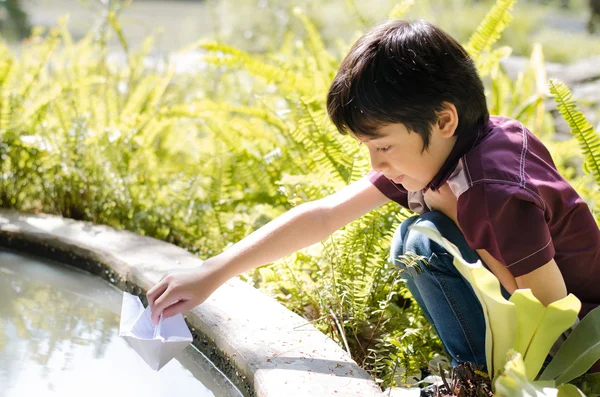 Little boy flytande papper båt — Stockfoto