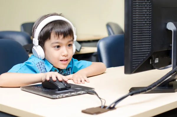 Liten pojke med headsetet i klassrummet med dator utbildning — Stockfoto