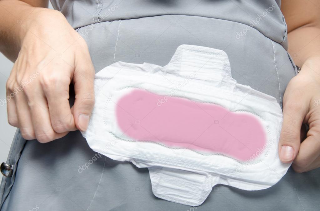 woman's hands holding a sanitary pad on green background close-u