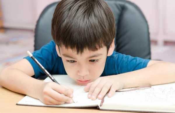 Kleine jongen huiswerk schrijven in de kamer — Stockfoto