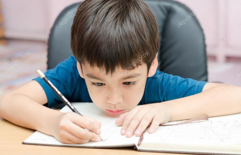 Little boy writing homework in the room 