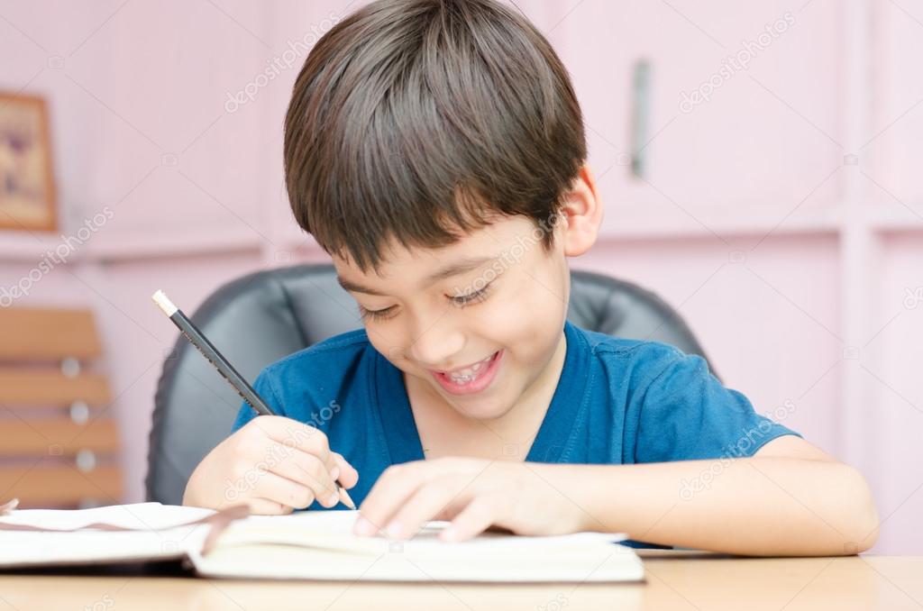 Little boy writing homework in the room with smiling