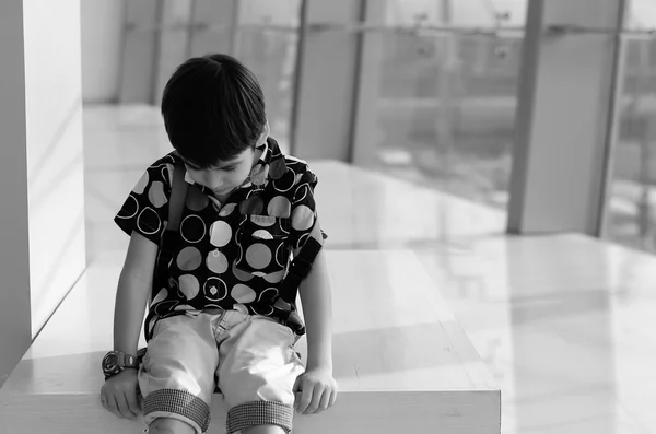 Menino sentado na cadeira com tristeza — Fotografia de Stock