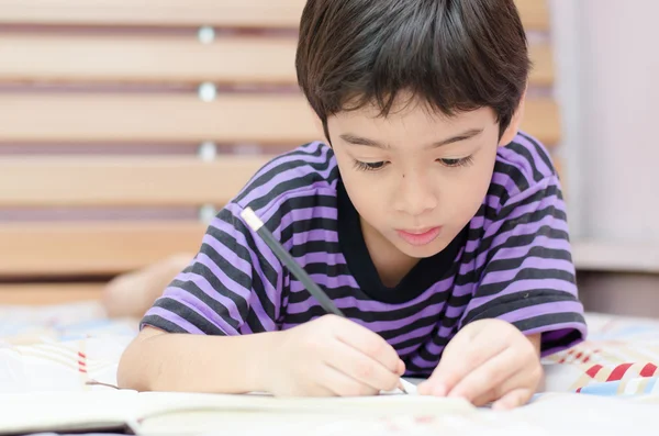 Маленький мальчик пишет дневник на кровати — стоковое фото