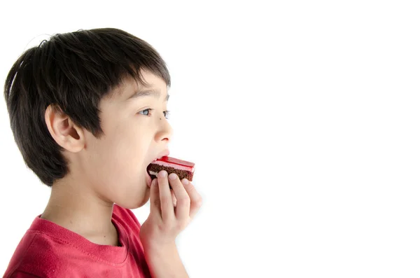 Little asian boy eating long cherry cake on white background — Stock Photo, Image