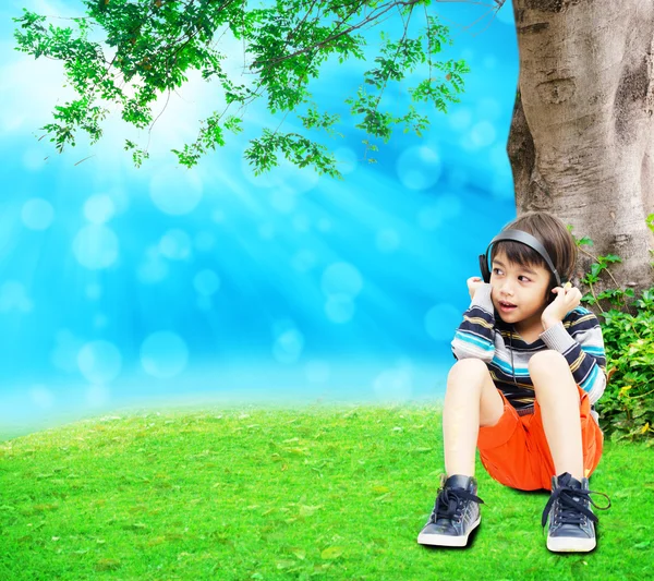 Little boy using headset in the park summer time fresh air — Stock Photo, Image