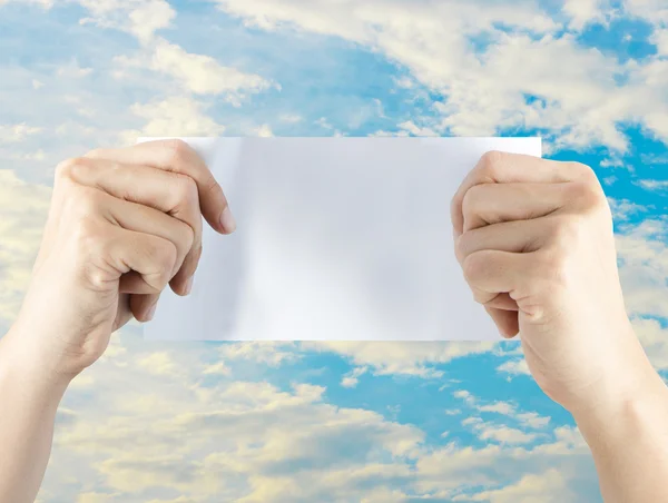 Mano sosteniendo papel vacío con cielo azul escena de la ciudad —  Fotos de Stock