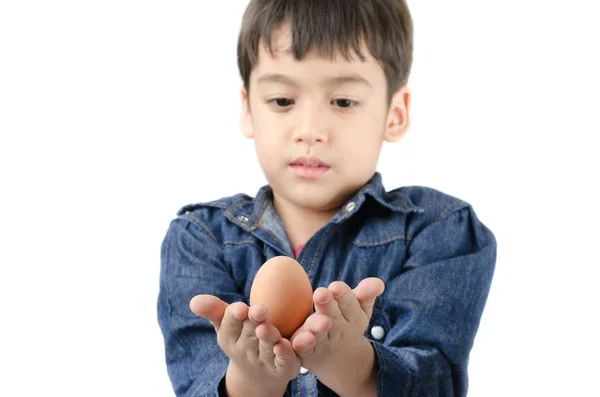 Kleine jongen bedrijf ei in de hand gezonde richten op ei op witte bac — Stockfoto