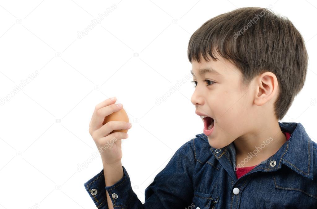 Little boy holding egg in hand mouth wide healthy on white backg