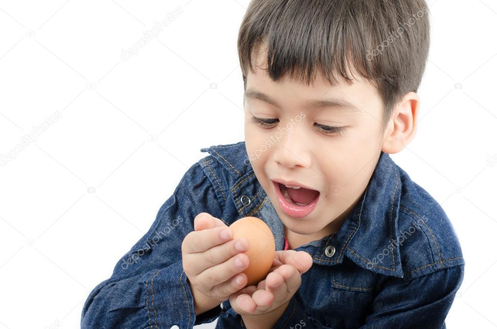 Little boy holding egg in hand mouth wide healthy on white backg