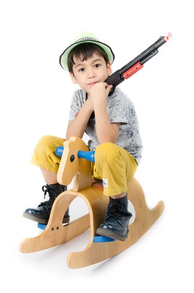 Kleine jongen praten houten paard met pistool speelgoed op witte achtergrond — Stockfoto