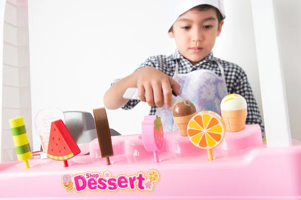 Little boy playing pretend as a saler in icecream shop