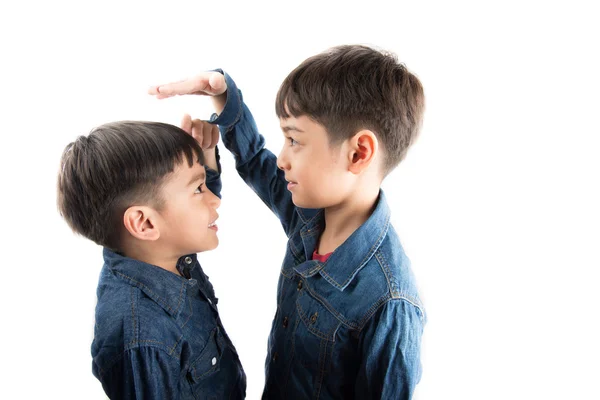 Adik laki-laki kecil saudara laki-laki memeriksa ada tinggi satu sama lain — Stok Foto