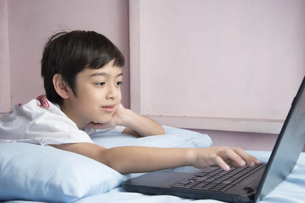 Niño pequeño usando portátil portátil en el dormitorio —  Fotos de Stock